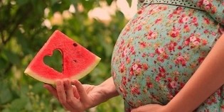 Watermelon slices in the hands of a pregnant woman